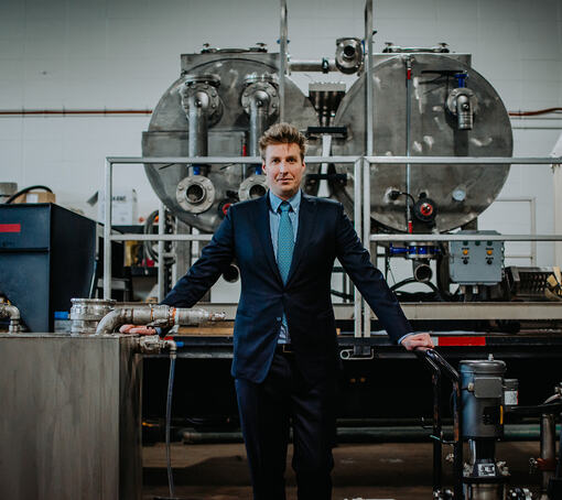 Martin Popiel debout dans son usine devant une grosse machine