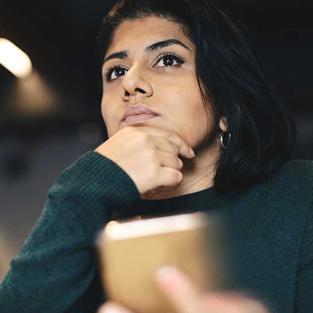 Femme perdue dans ses pensées devant son laptop tard en soirée